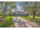 Wide brick driveway leading to a grand home, framed by mature trees and lush green lawns at 4121 Highland Park Cir, Lutz, FL 33558