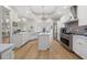 Bright white kitchen with stainless steel appliances, island, and modern chandelier at 4121 Highland Park Cir, Lutz, FL 33558