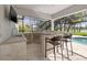Outdoor kitchen with stainless steel appliances, bar seating, and views of the pool and lake at 4121 Highland Park Cir, Lutz, FL 33558