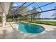 Backyard pool area with a screened enclosure overlooking a serene lake and lush landscaping at 4121 Highland Park Cir, Lutz, FL 33558