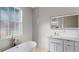 Bright bathroom with double vanity, soaking tub, stylish fixtures, and a large window bringing in natural light at 5051 Gevalia Dr, Brooksville, FL 34604