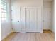 Bedroom featuring light wood flooring, bright window with white trim, and closet storage at 5051 Gevalia Dr, Brooksville, FL 34604