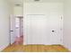 Bright bedroom featuring light hardwood floors, white walls, and bi-fold closet doors at 5051 Gevalia Dr, Brooksville, FL 34604