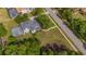 Aerial view of a blue house with a gray roof, large lawn, screened pool, and lush trees at 5913 Flatwoods Manor Cir, Lithia, FL 33547