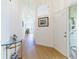 Bright hallway with light wood floors, white walls, decorative glass door and picture frames at 6208 Country Club Way, Sarasota, FL 34243