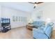 Bright living room with a ceiling fan, plantation shutters, light wood floors, and comfortable blue seating at 6208 Country Club Way, Sarasota, FL 34243