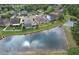 A high angle aerial view of the property, surrounded by lush greenery, trees, and a tranquil pond at 6303 Hawk Grove Ct, Wesley Chapel, FL 33545