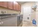 A well-equipped laundry room features upper cabinets, modern appliances, and a utility sink at 6303 Hawk Grove Ct, Wesley Chapel, FL 33545