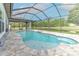 A large screened in pool with a stone deck offers a relaxing view of the pond and backyard at 6303 Hawk Grove Ct, Wesley Chapel, FL 33545