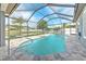 A screened pool boasts a stone pool deck with views of a pond and mature landscaping at 6303 Hawk Grove Ct, Wesley Chapel, FL 33545