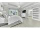 Spacious main bedroom featuring tray ceilings, a sleek modern light fixture, ensuite bathroom and light wood-look flooring at 6518 Salt Creek Ave, Apollo Beach, FL 33572