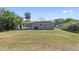 Expansive backyard with a covered carport, shed, grassy area, and trees on a sunny day at 7139 Adare Dr, New Port Richey, FL 34653