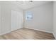 Minimalist bedroom with hardwood floors, double-door closet, and natural light from the window at 7139 Adare Dr, New Port Richey, FL 34653