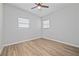 Bright bedroom featuring wood-look floors, a ceiling fan, and natural light from the windows at 7139 Adare Dr, New Port Richey, FL 34653