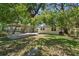 Backyard with a partial view of the house and carport surrounded by trees at 8215 N 12Th St, Tampa, FL 33604