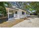 A charming white home with a covered porch and a spacious driveway leading to a carport at 8215 N 12Th St, Tampa, FL 33604