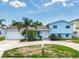 Charming light blue two-story home featuring a circular driveway and lush tropical landscaping at 8722 Hickorywood Ln, Tampa, FL 33615