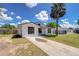Charming white single-story home with a long driveway and a lush green lawn under a sunny sky at 911 Kirkcaldy Way, Valrico, FL 33594