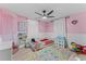 Cheerful pink bedroom with ceiling fan, play area and plenty of natural light at 3748 Redwood Dr, Holiday, FL 34691