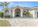 Elegant home featuring a double-door entry, arched windows, and manicured landscaping at 13403 Bolton Ct, Spring Hill, FL 34609