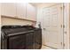A well-lit laundry room with black washer and dryer and overhead cabinets at 13403 Bolton Ct, Spring Hill, FL 34609