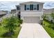 Two-story home features a two-car garage, well-manicured lawn, and charming front yard landscaping at 17006 Wave Tressle Pl, Wimauma, FL 33598