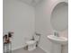 Elegant powder room featuring a pedestal sink, toilet, and decorative mirror in neutral tones at 17006 Wave Tressle Pl, Wimauma, FL 33598