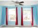 Bedroom boasting two windows with red curtains, a ceiling fan, and light blue walls at 17833 Althea Blue Pl, Lutz, FL 33558