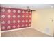 Spacious bedroom with red accent wall with floral design and neutral carpet flooring under a ceiling fan at 17833 Althea Blue Pl, Lutz, FL 33558