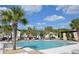 Inviting community pool with poolside seating, lush palm trees, and clear blue sky at 17833 Althea Blue Pl, Lutz, FL 33558
