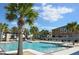 Community pool with lounge chairs and palm trees under a blue sky with clouds at 17833 Althea Blue Pl, Lutz, FL 33558