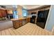 Open kitchen with tile flooring, black appliances, and wood cabinets, adjacent to the living area at 23059 Geneva Rd, Land O Lakes, FL 34639