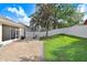 Backyard includes a brick patio, grassy area, white fencing, and tree with custom brick mulch bed at 2605 Durant Trails Blvd, Dover, FL 33527