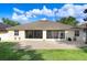 Back facade featuring a sunroom addition and brick patio, enhanced by a lush lawn at 2605 Durant Trails Blvd, Dover, FL 33527