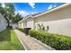 Exterior side view featuring manicured bushes, a brick pathway, and neutral-colored stucco siding at 2605 Durant Trails Blvd, Dover, FL 33527