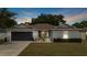 Charming single-story home with well-manicured lawn, gray exterior, and a sleek, dark gray garage door at 3011 49Th S Ter, St Petersburg, FL 33712