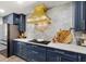 Modern kitchen features navy cabinets, white countertops, and a striking gold range hood over the cooktop at 3011 49Th S Ter, St Petersburg, FL 33712