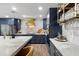 Modern kitchen boasts navy cabinets, white countertops, stainless steel appliances, and a striking gold range hood at 3011 49Th S Ter, St Petersburg, FL 33712