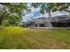 Wide view of the backyard with a screened in patio area and green lawn, lined with mature trees at 4207 Fairway Run, Tampa, FL 33618