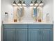 A charming bathroom featuring a double sink vanity with elegant blue cabinetry and stylish fixtures and wallpaper at 4215 Saltwater Pearl Way, Cortez, FL 34215