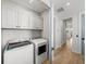 Well-lit laundry room with white cabinets and modern washer and dryer units at 4215 Saltwater Pearl Way, Cortez, FL 34215