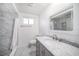 Bright bathroom with marble vanity, framed mirror, and tiled shower at 7136 Isle Dr, Port Richey, FL 34668