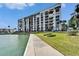 Exterior view of a multi-story condo building on the waterfront with beautiful green spaces at 7700 Sun Island S Dr # 107, South Pasadena, FL 33707