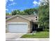 Two-story townhouse featuring a two-car garage and lush landscaping in the front yard at 8901 Casablanca Way, Tampa, FL 33626