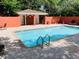 Community pool featuring light-blue water, brick pavers, and an orange clubhouse nestled among mature trees at 8901 Casablanca Way, Tampa, FL 33626