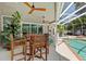 Inviting screened-in pool patio with wood furniture, ceiling fans, and view of a sparkling pool at 9322 Wellington Park Cir, Tampa, FL 33647