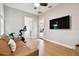 Spacious flex room perfect for working out, featuring wood floors, a ceiling fan, and a large TV at 9801 Pine Leaf Ln, Dade City, FL 33525