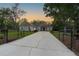 Charming single Gathering home at dusk with long driveway, mature trees, and well-manicured lawn at 9801 Pine Leaf Ln, Dade City, FL 33525