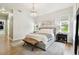 Bright main bedroom with a gray bed frame, chandelier, and natural light from two windows at 9801 Pine Leaf Ln, Dade City, FL 33525