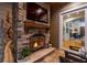 Warm and inviting outdoor space featuring a stone fireplace and a glimpse of the living areas at 9801 Pine Leaf Ln, Dade City, FL 33525